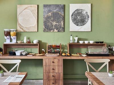 Bufet z płatkami, sokami i ciastkami na tle zielonej ściany w sali śniadaniowej hotelu