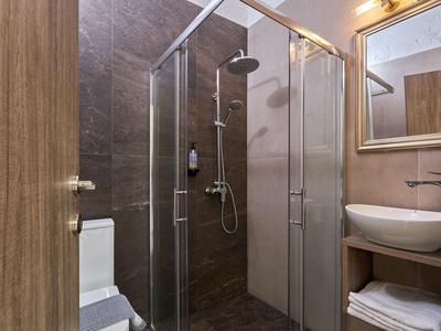 Nowoczesna łazienka z szklaną prysznicem, umywalką na drewnianej konsoli i toaletą.