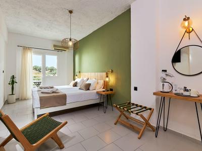 Jasny pokój hotelowy z zieloną ścianą akcentową, wygodnym łóżkiem i krzesłem.