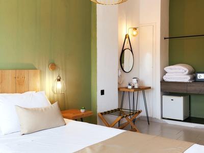 Sypialnia z zieloną ścianą, drewnianym łóżkiem, lustrem i miejscem do przechowywania w pokoju hotelowym.