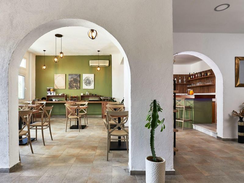 Przytulna jadalnia z zieloną ścianą, drewnianymi stołami i krzesłami, widok wewnętrzny.