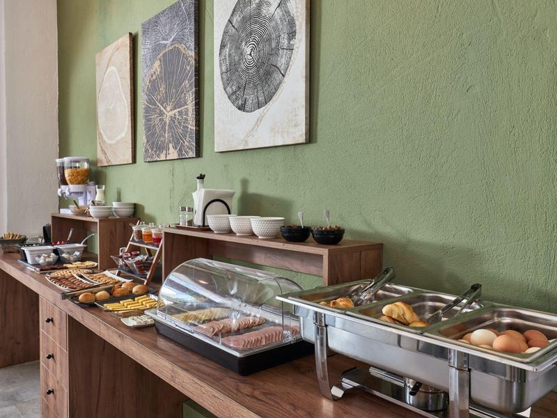 Bufet z różnymi potrawami i napojami przy zielonej ścianie w jadalni.