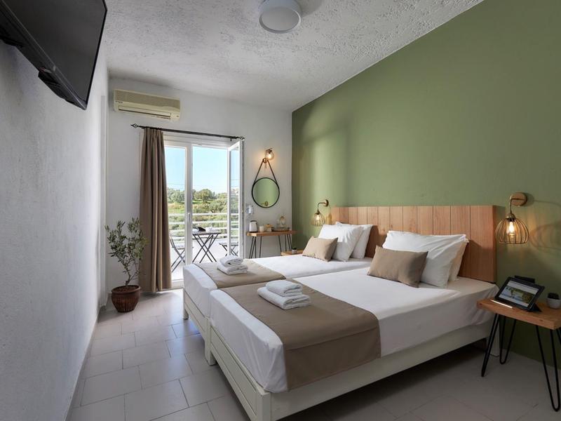 Nowoczesny pokój hotelowy z łóżkiem podwójnym, zieloną ścianą i balkonem z widokiem na morze.