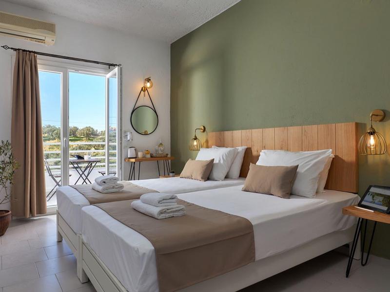 Nowoczesny pokój hotelowy z łóżkiem podwójnym, balkonem i zieloną ścianą akcentową.