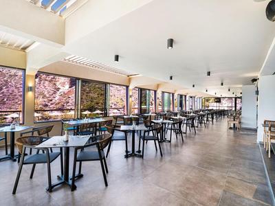 Cafetteria moderna e luminosa con grandi finestre e molti tavoli e sedie.