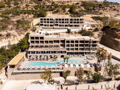 Meerdere verdiepingen tellend hotel met zwembad en zonneterrassen in rotsachtig landschap.