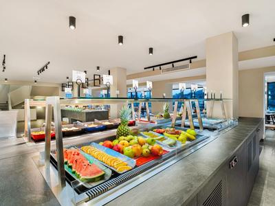 Modern ontbijtbuffet met vers fruit en sappen in een lichte restaurantruimte.