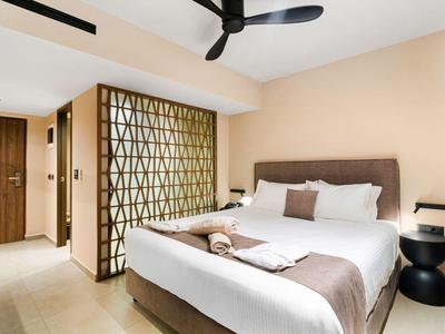 Moderne hotelkamer met groot bed, plafondventilator en decoratieve kamerverdeler.