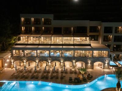 Hôtel moderne avec piscine éclairée et salons sous la lumière du soir.