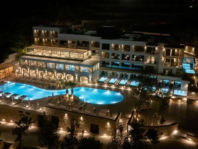 Hotelcomplex 's nachts met verlichte zwembaden en buitenzitjes.