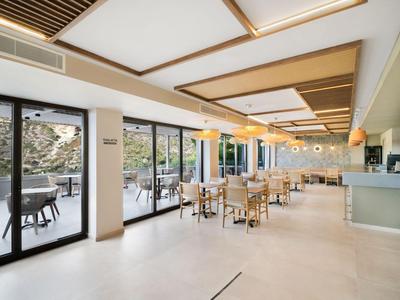 Ristorante hotel luminoso e moderno con grandi finestre e terrazza esterna.