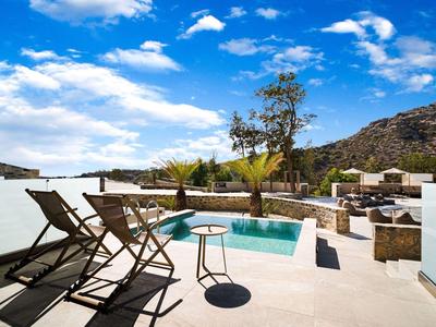 Terras met zwembad, ligstoelen en bergzicht onder een heldere lucht.