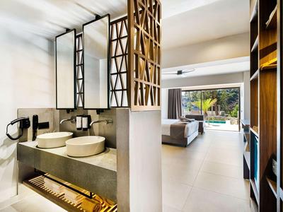 Modern hotelbadkamer met twee wastafels en uitzicht op de aangrenzende woonkamer en terras.