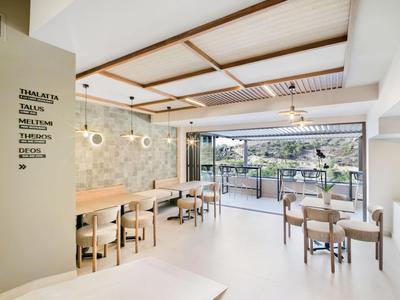 Ristorante luminoso e moderno con tavoli e sedie, vista aperta su terrazza e natura.