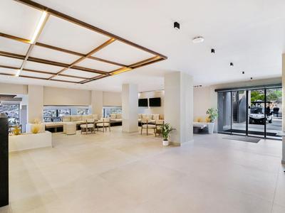 Lichte hotel lobby met open ruimte, zitgedeeltes en grote ramen voor daglicht.