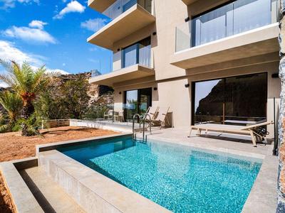 Modern vakantiehuis met klein zwembad en terras onder blauwe lucht.