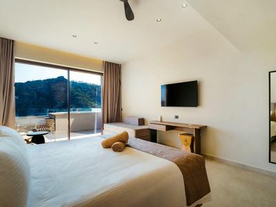 Lichte hotelkamer met groot bed, wand-tv en uitzicht op de bergen door glazen deuren.