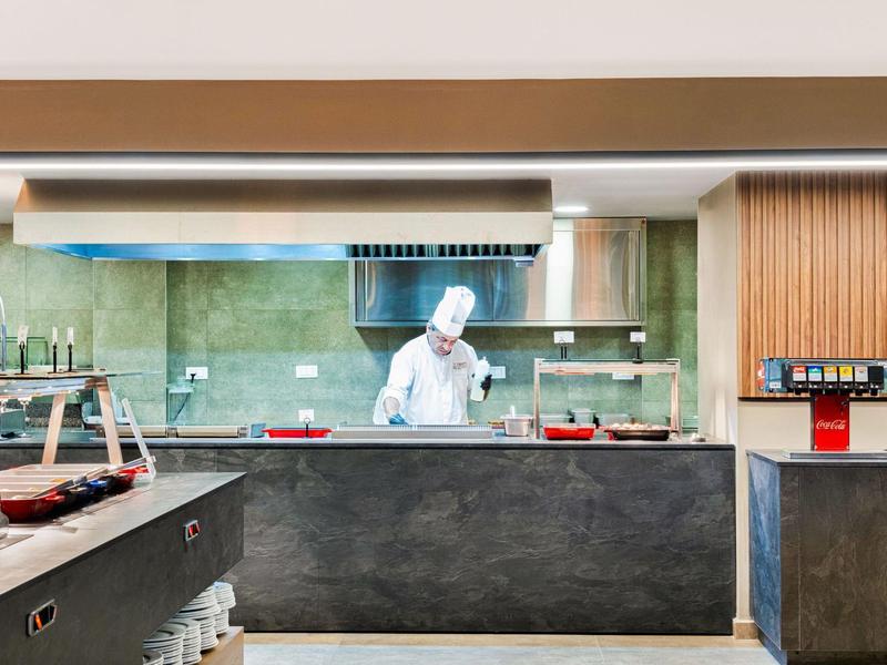 Kok in wit uniform bereidt eten voor in een moderne restaurantkeuken.