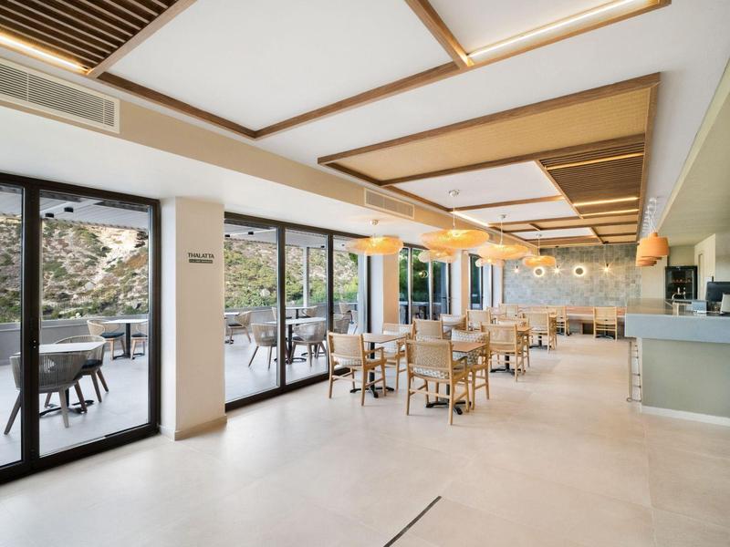 Lichte en moderne eetzaal met houten meubels en grote panoramische ramen.