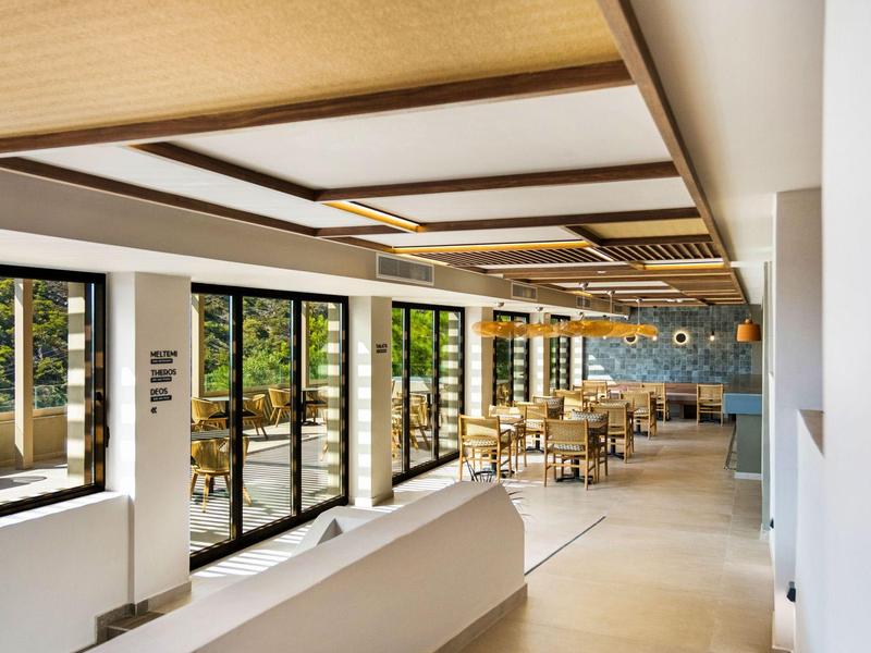 Lichte, moderne eetruimte met grote ramen en houten meubels, uitzicht op groene omgeving.