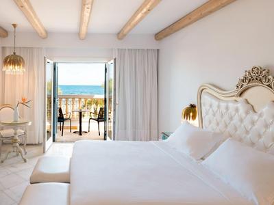 Camera luminosa con letto matrimoniale, pareti bianche e vista sulla terrazza e sul mare.