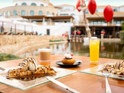 Stůl s různými dezerty a nápoji v venkovní části hotelu.