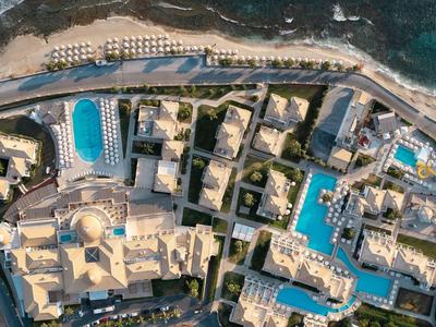 Letecký pohled na resort s bazény, budovami a pobřežím u moře.