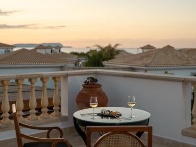 Terasa se stolem, dvěma sklenicemi vína a výhledem na střechy při západu slunce