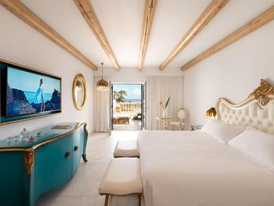 Světý a elegantní hotelový pokoj se dvěma postelemi, televizí na zdi a výhledem na terasu.