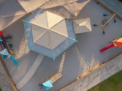 Ptačí pohled na dětské hřiště s pískem, vícepodlažní stavbou a herním vybavením