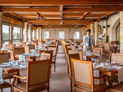 Großes Restaurant mit Holzmöbeln und vielen Fenstern, Servicepersonal bereitet vor.