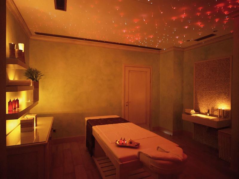 Accogliente stanza spa con illuminazione soffusa, lettini da massaggio e candele.