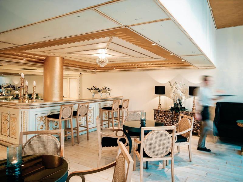 Area bar elegante in hotel con sgabelli e sedute accoglienti in luce calda.