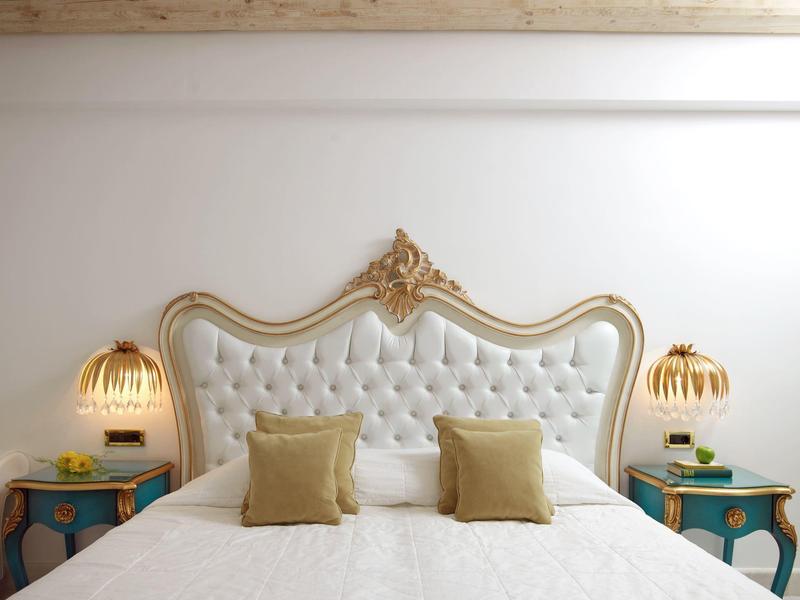 Elegante letto matrimoniale con testiera decorata e due comodini con lampade in una camera moderna