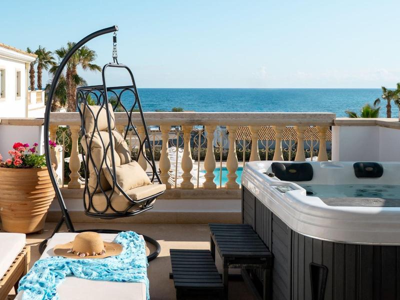 Terrazza con sedia sospesa, vasca idromassaggio e vista mare in una giornata di sole