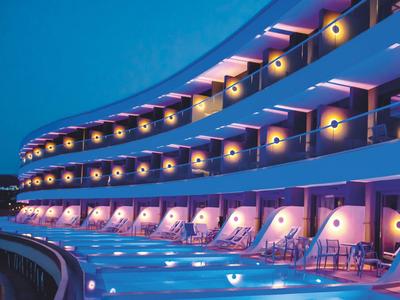 Hotel mit beleuchtetem Pool und Balustraden, runde Lichtquellen an modernem Gebäudedach.