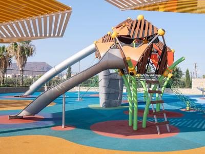 Bunter moderner Spielplatz mit Rutschen, Klettergerüst und Schattensegeln unter blauem Himmel.