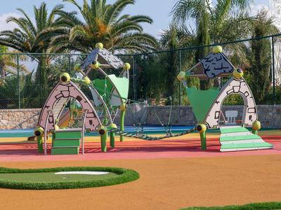 Bunter Spielplatz mit grünen Palmen im Hintergrund und Rutschen in Form von Häusern.