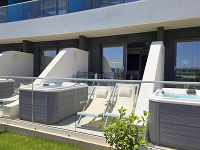 Terrasse mit zwei Liegestühlen, Whirlpool und Glashandlauf an einem Hotelbalkon