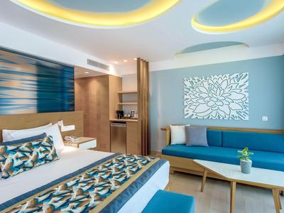 Modern eingerichtetes Hotelzimmer mit Doppelbett, blauem Sofa und dekorativem Wandbild.