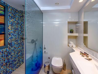 Modernes Badezimmer mit Mosaikfliesen, Dusche, Toilette und Waschbecken mit Spiegel.