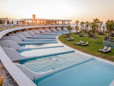 Luxuriöse Hotelpools mit Liegen und Blick auf den Sonnenuntergang und Meer