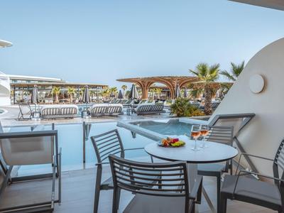 Balkon mit Tisch, Stühlen und Blick auf Pool und Terrasse eines Hotels.