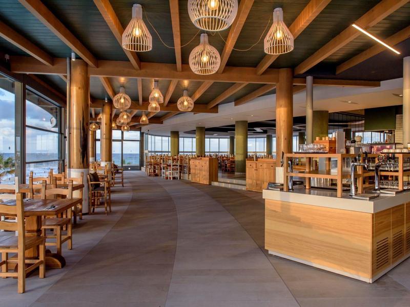 Amplio comedor moderno con muebles de madera y grandes ventanas en un hotel.