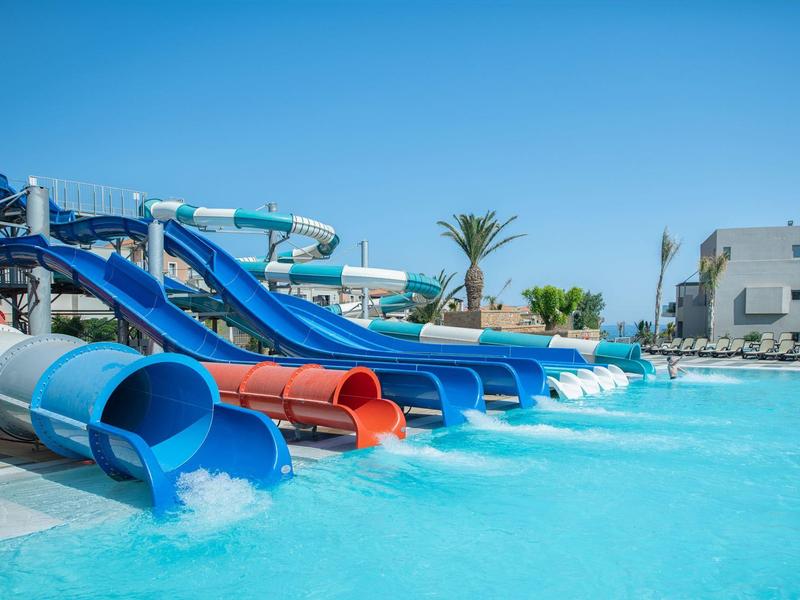 Múltiples toboganes acuáticos coloridos desembocan en una piscina bajo un cielo despejado.