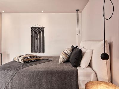 Chambre d'hôtel moderne avec lit double, couverture grise et suspension murale décorative.