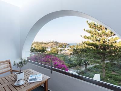 Balcon avec table en bois et vue sur des arbres et des collines sous un arc blanc