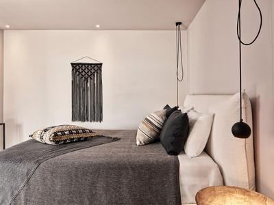 Camera da letto con letto grande, copriletto grigio e decorazioni murali in una stanza luminosa.