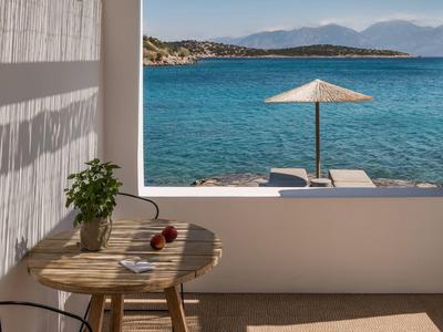 Vue sur la mer avec parasol et chaises longues depuis un balcon avec table et chaise.