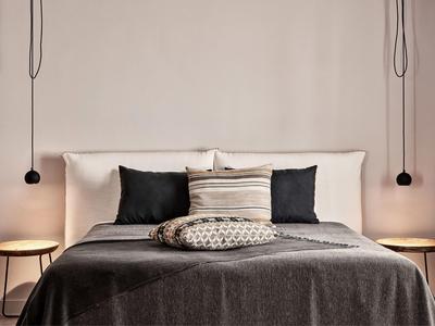 Chambre moderne avec lit double, murs blancs et éclairage minimaliste.